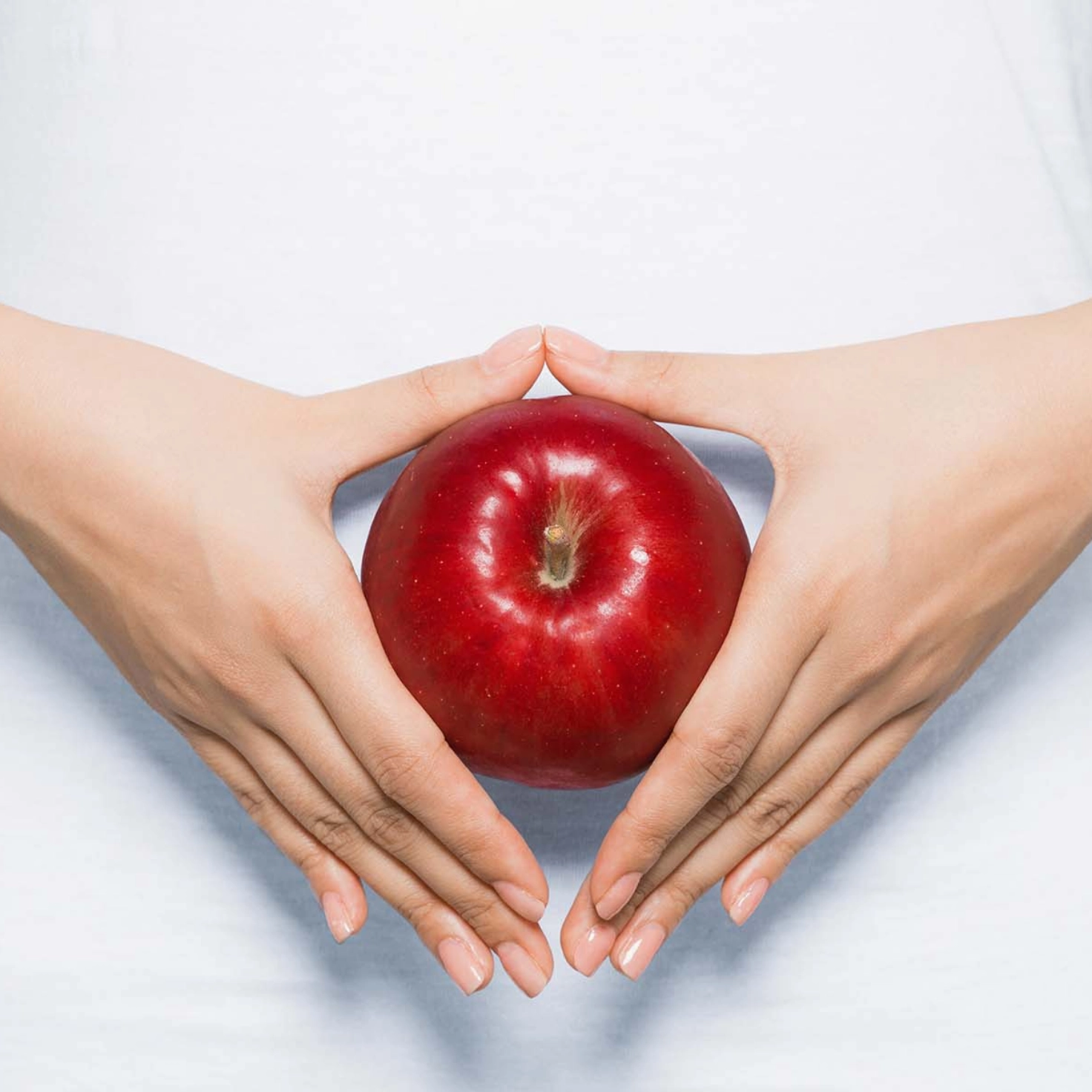 A woman holds an apple in front of her belly