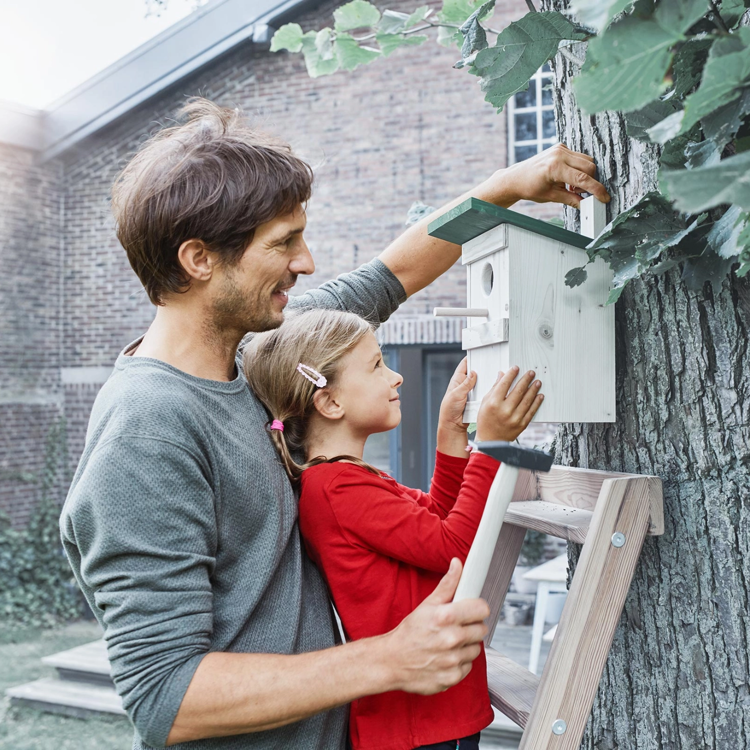 Father and daughter hang a birdhouse together