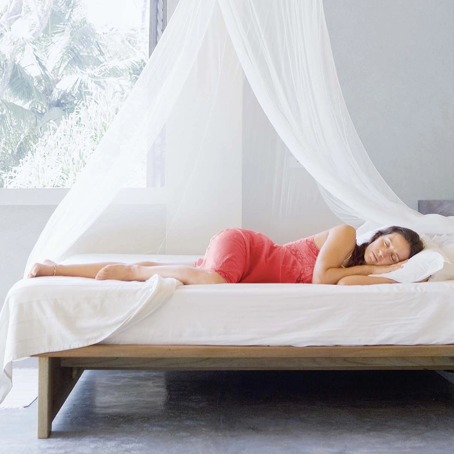 A woman sleeps under a mosquito net in summer.