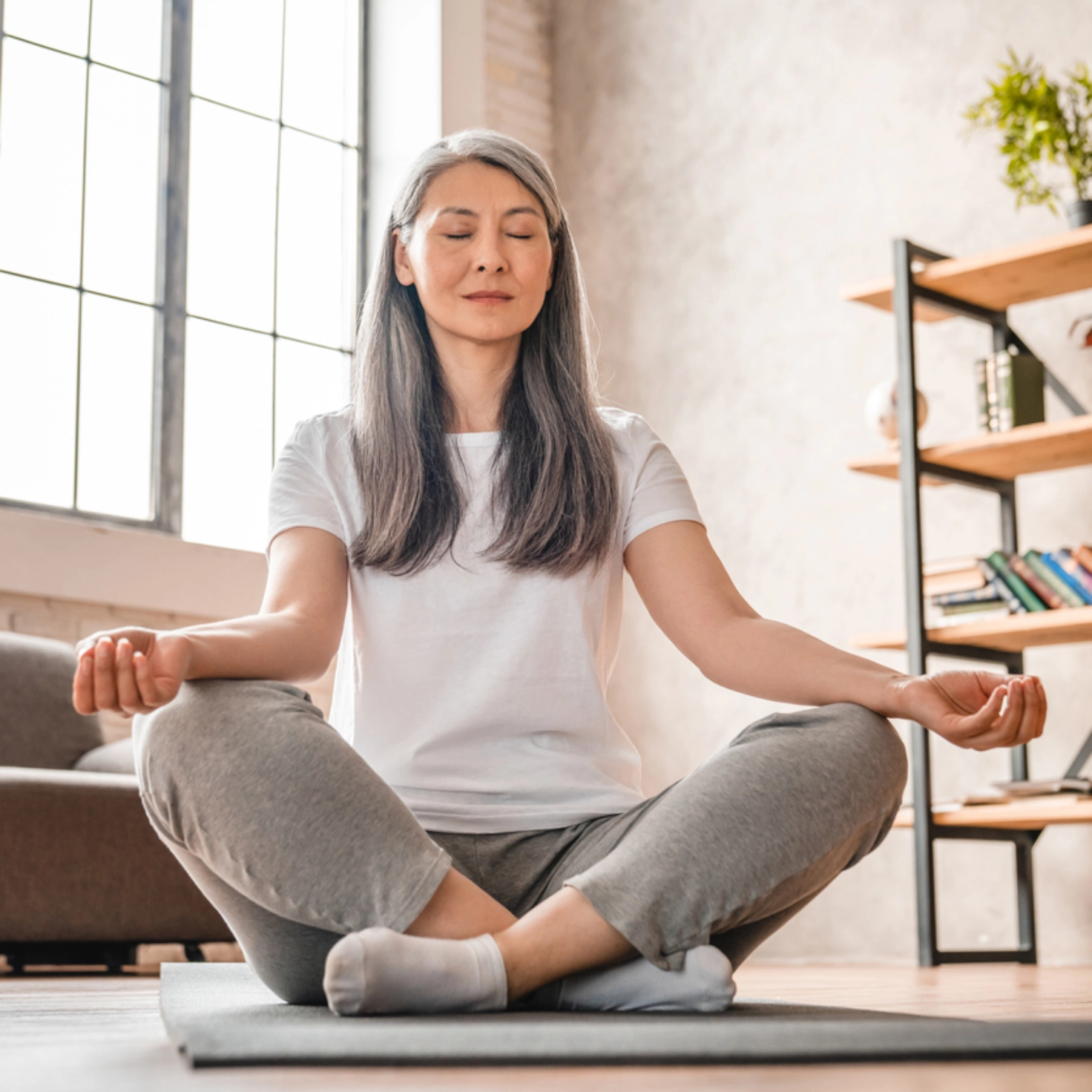 Une femme aux longs cheveux gris en train de méditer
