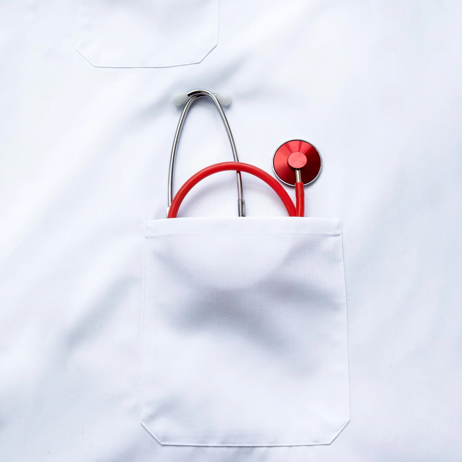 A stethoscope protrudes from the breast pocket of a doctor's coat.