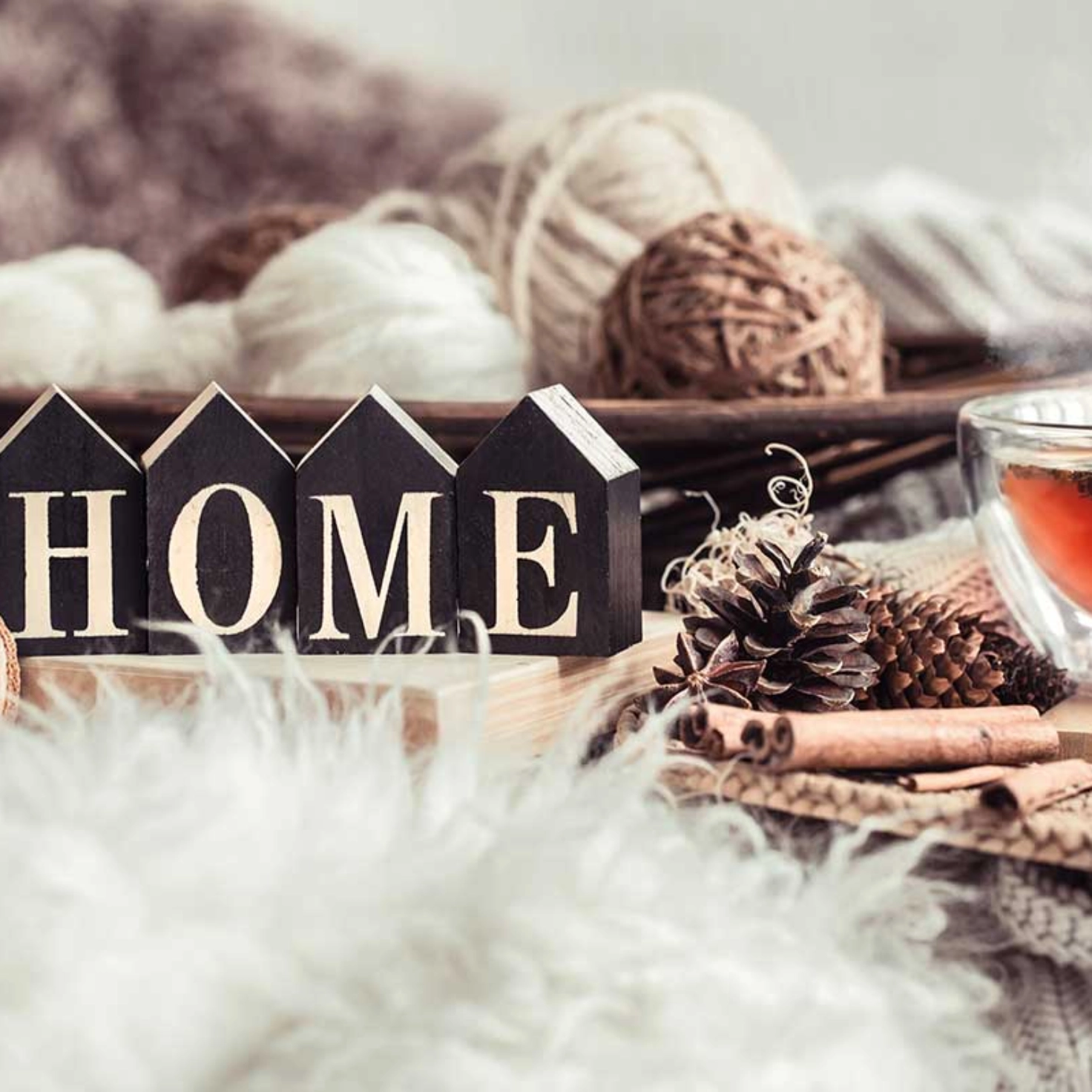 A cup of tea surrounded by various decorative objects, including four small houses with the letters HOME