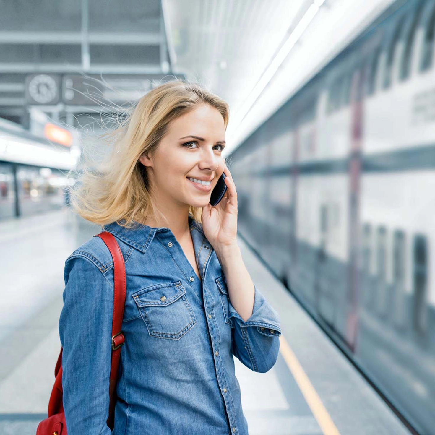 Une femme téléphone avec son portable sur un quai de gare<br/>
