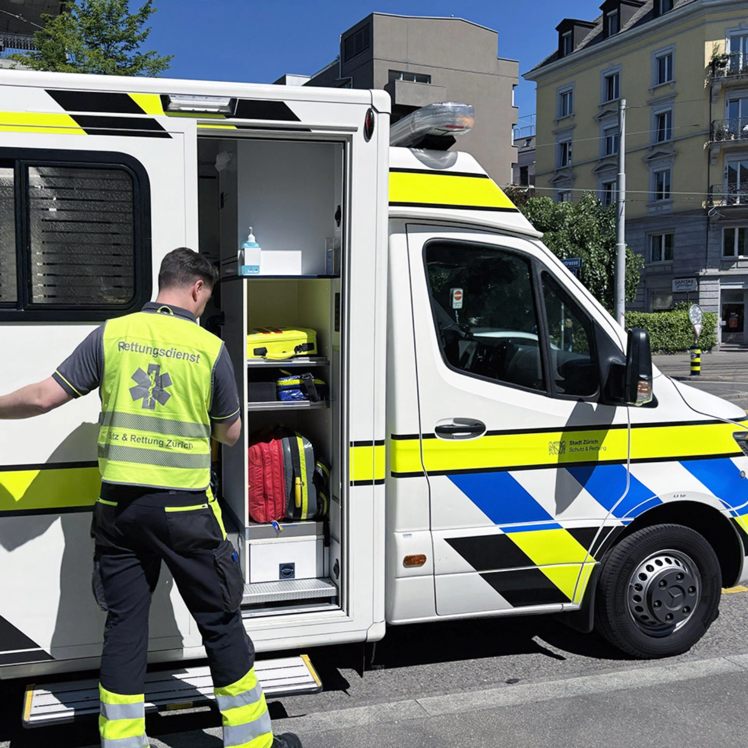 Ein Rettungssanitäter mit gelber Weste öffnet die Seitentür eines Rettungswagens