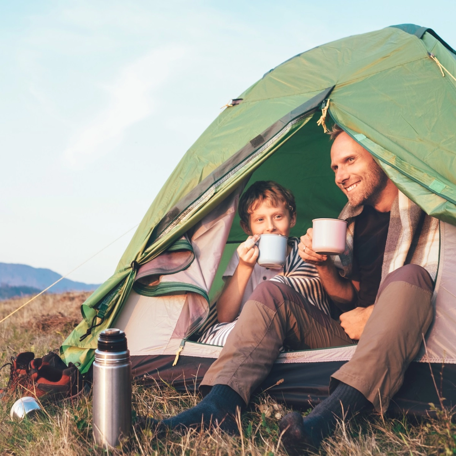 Père et fils faisant du camping sous une tente.
