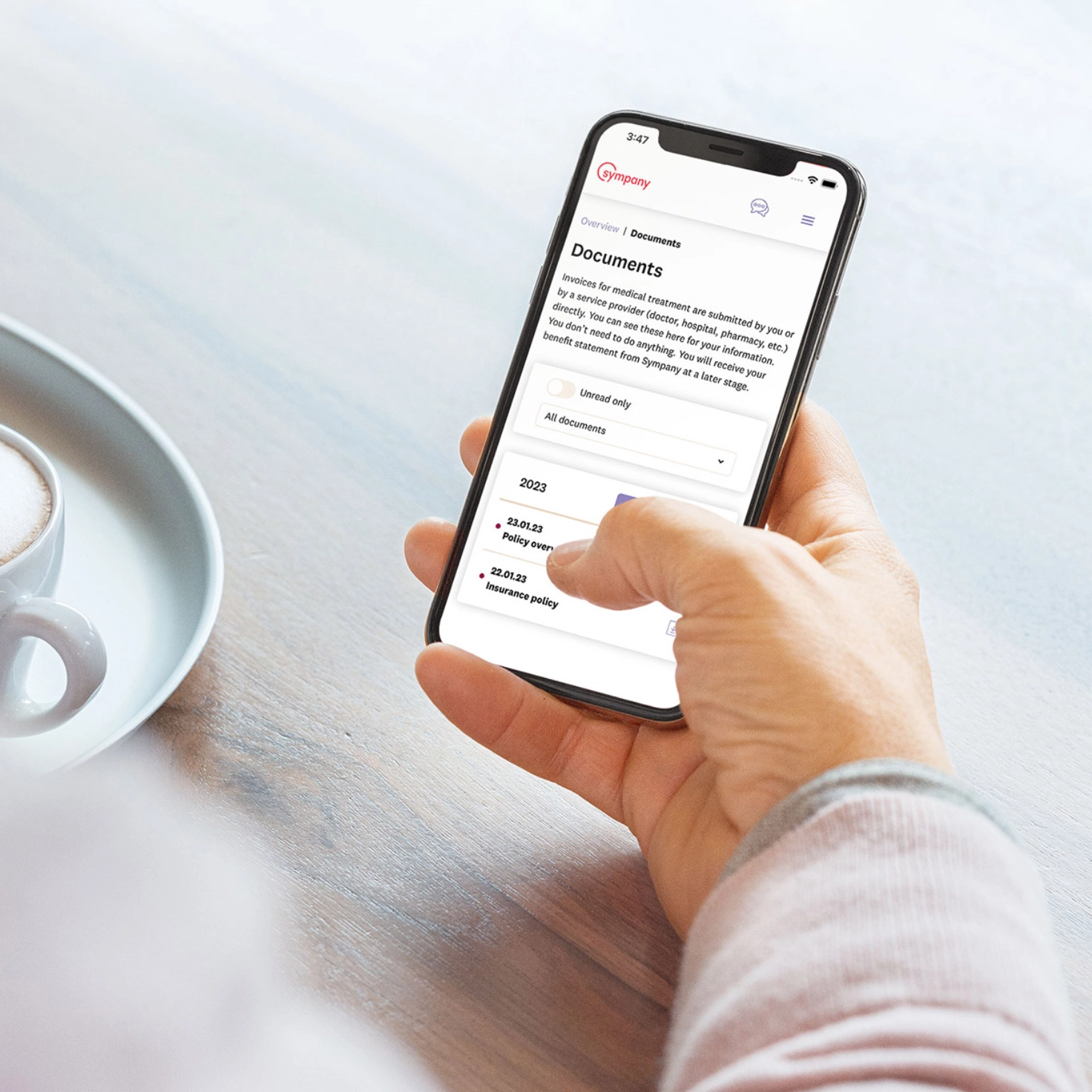A person is holding a smartphone. The screen shows the mySympany customer portal in the English language version.