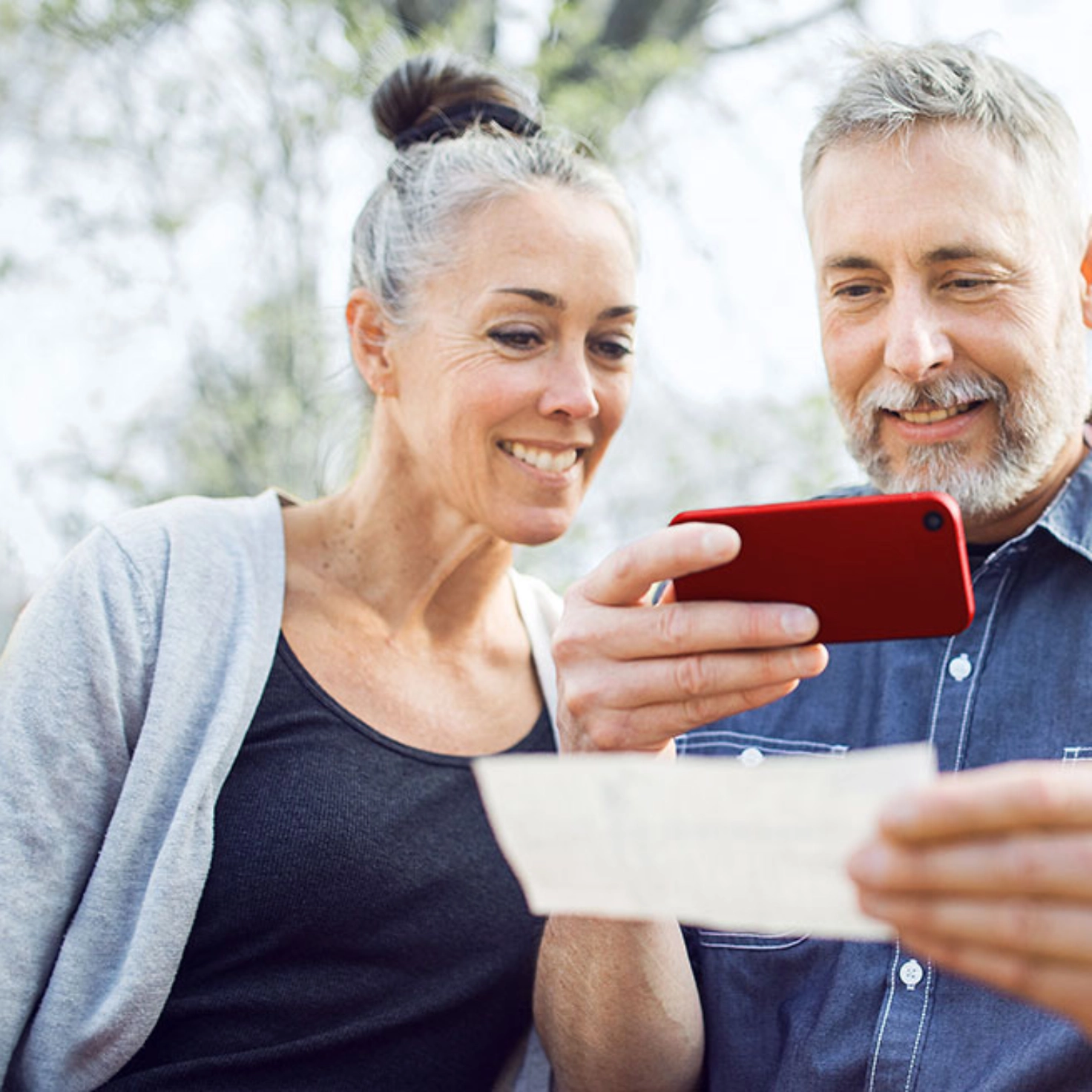 Une femme regarde un homme prendre une photo d'un document avec un smartphone.