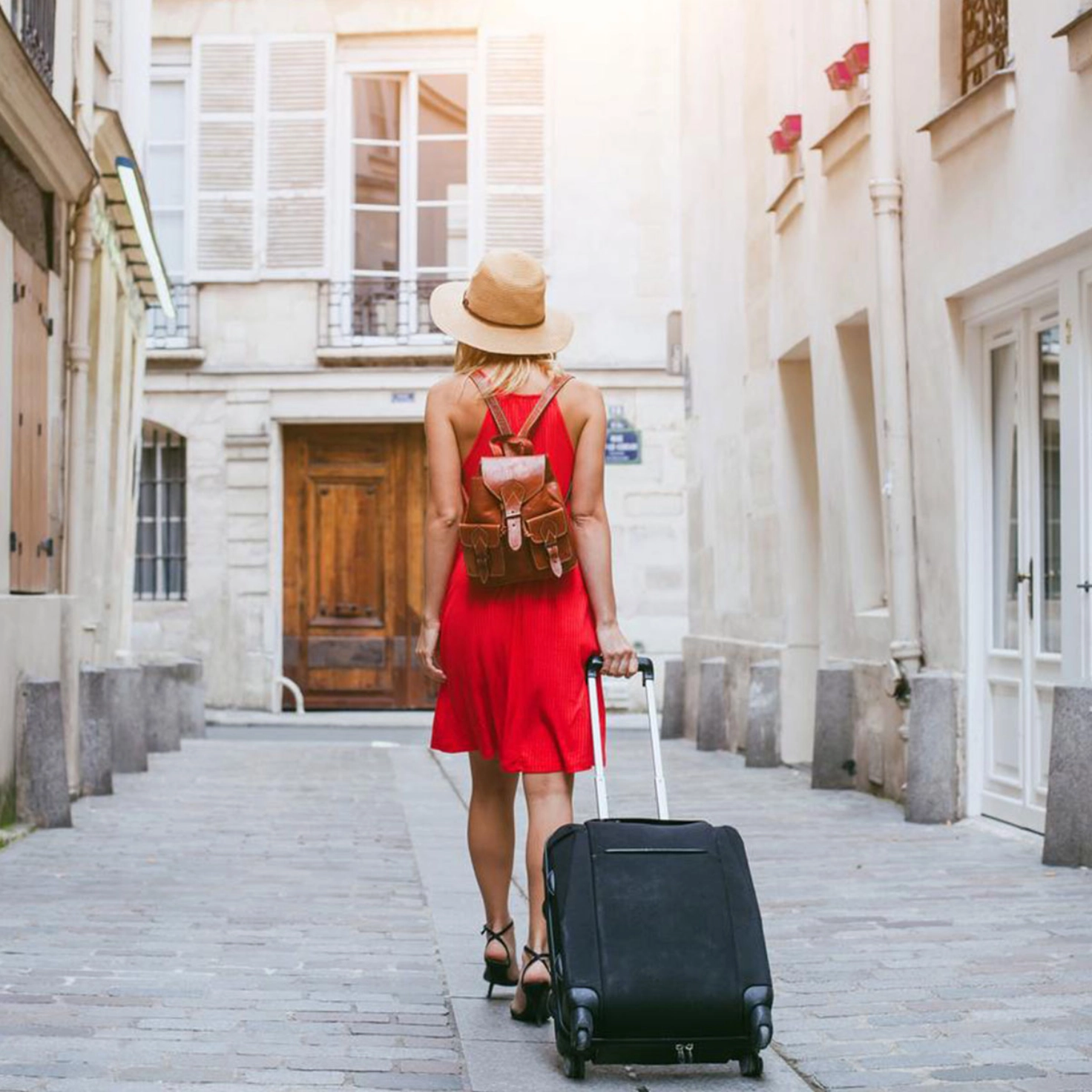 Une touriste se promène dans une ruelle étroite avec une valise à roulettes