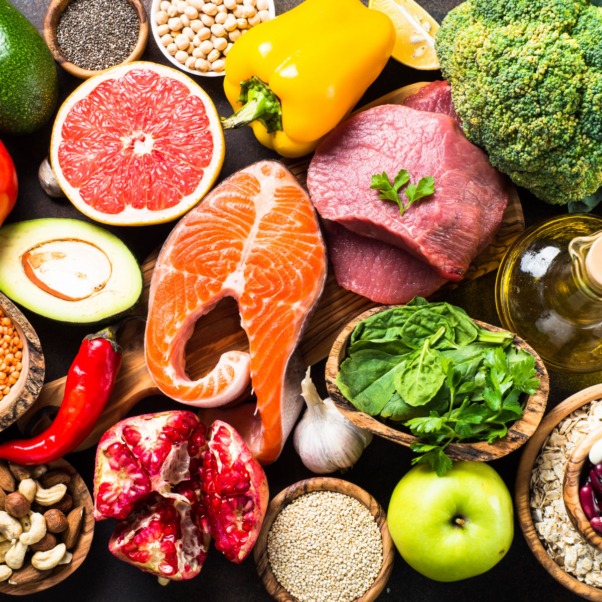 A piece of salmon surrounded by several portions of fruit and vegetables