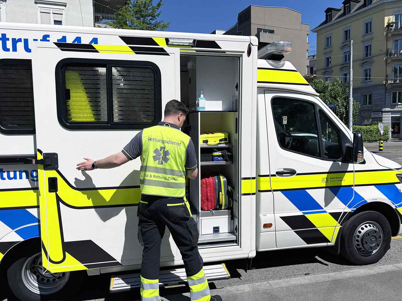 Un samaritain en gilet jaune ouvre la porte latérale d'une ambulance