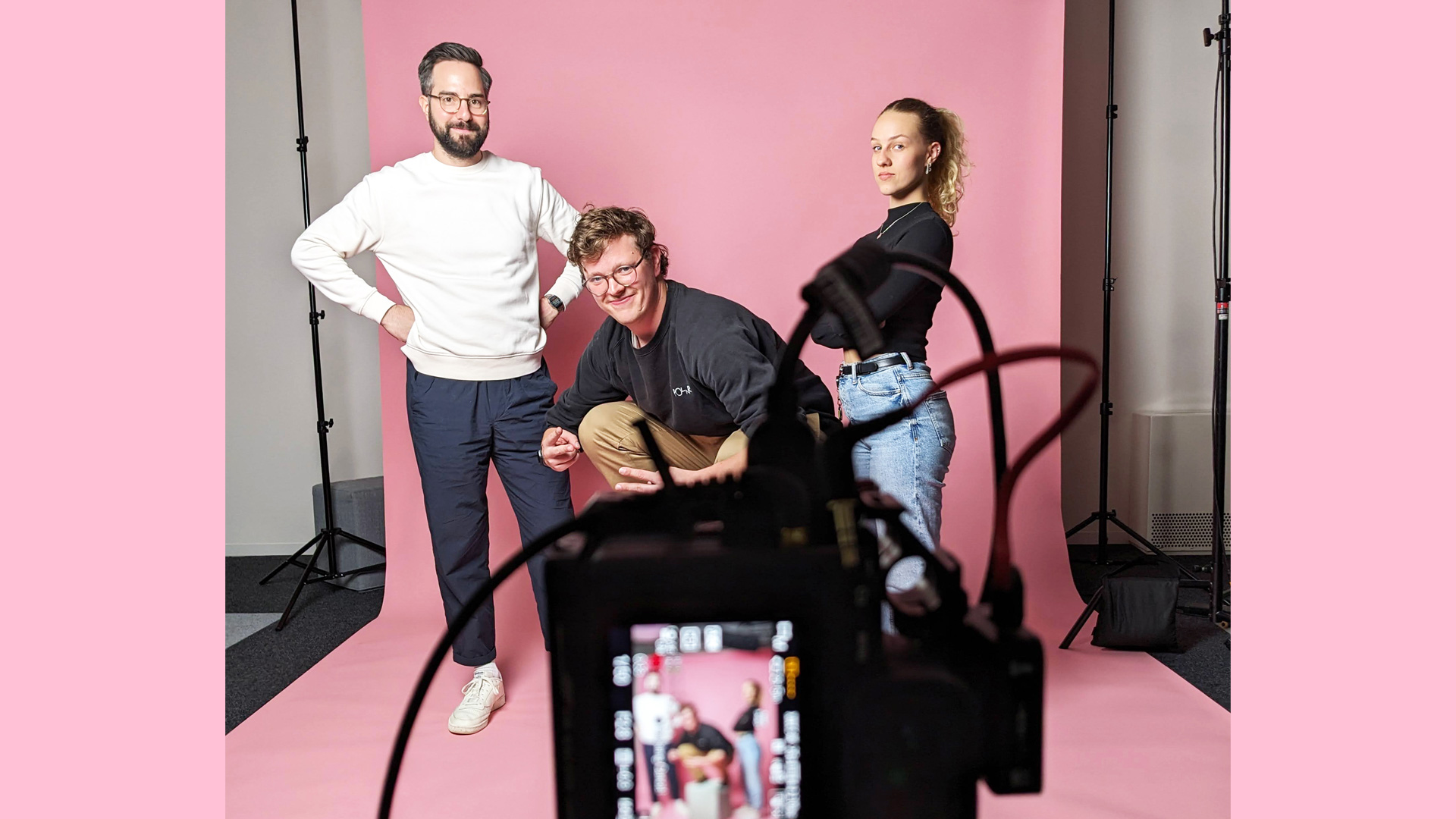 Snapshot from the video shoot with the Sympany Customer Council: Two men and a woman can be seen in the background in front of a pink screen, with the video camera in the foreground